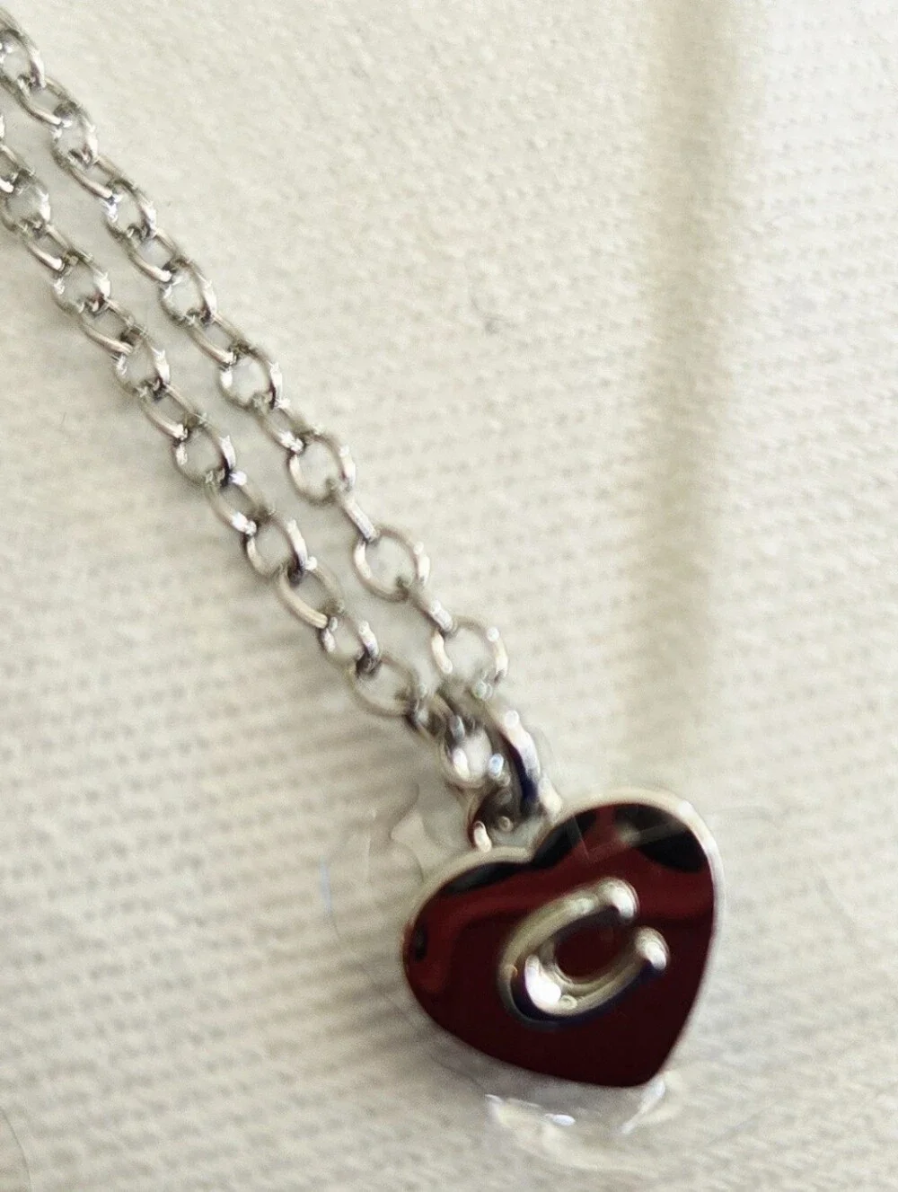 Coach silver-tone necklace features a small, heart pendant with COACH tag